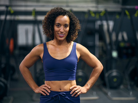 A young adult woman in a gym cross training.