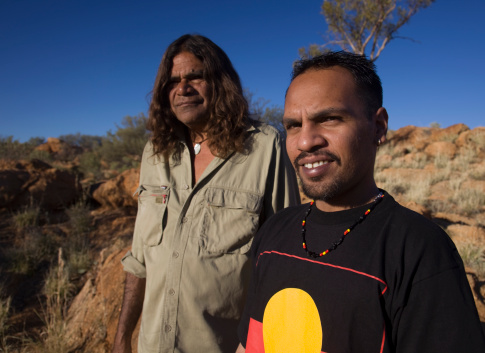 A young and older Aboriginal man standing together. Could be father and son.