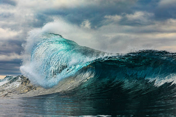 istock Powerful teal wave breaking in the ocean with a dark cloudy, sky 1739490971