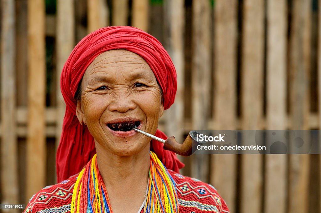 Karen Woman Smoking Pwo Karen hill tribe woman in north Thailand smoking a pipe and wearing traditional clothing. Adult Stock Photo