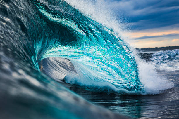istock Powerful teal blue wave breaking in the ocean with a dark cloudy, sky 1739491514