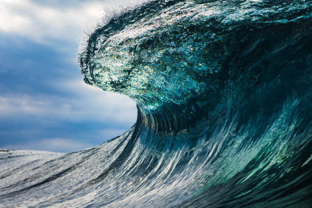istock Powerful teal blue wave breaking in the ocean with a dark cloudy, sky 1739491518