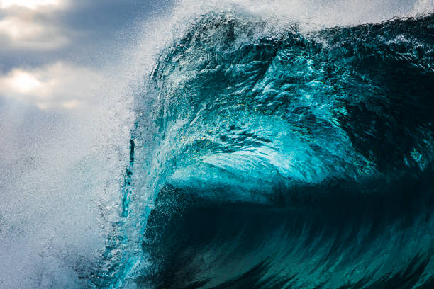 istock Powerful teal blue wave breaking in the ocean with a dark cloudy, sky 1739491534