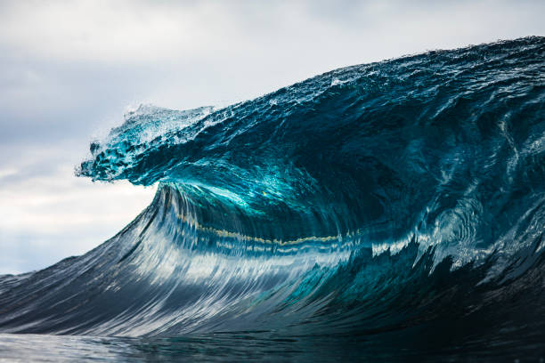 istock Powerful teal blue wave breaking in the ocean with a dark cloudy, sky 1739492057