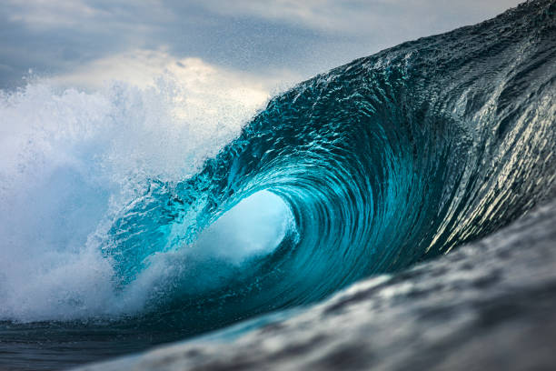 istock Powerful teal blue wave breaking in the ocean with a dark cloudy, sky 1739492087