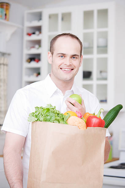 istock Groceries and Man in Kitchen eating Apple 173949284