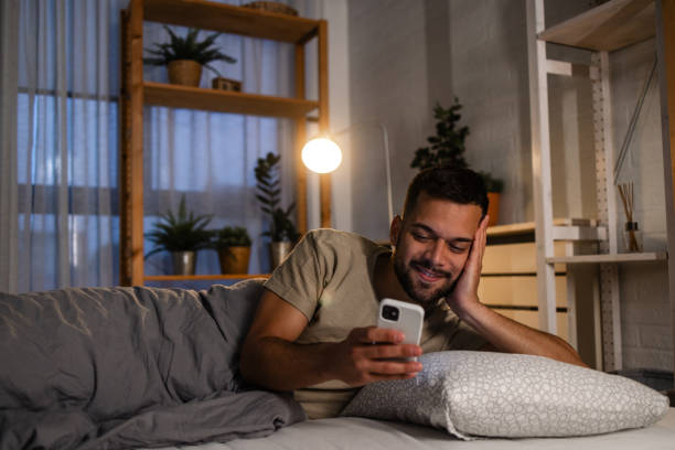 istock A young man is smiling while looking at the smart phone in bed 1739493902