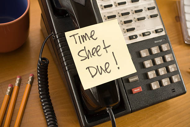 Time sheet due written on a sticky note stuck to a telephone stock photo