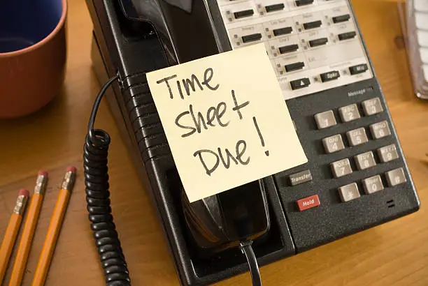 Photo of Time sheet due written on a sticky note stuck to a telephone