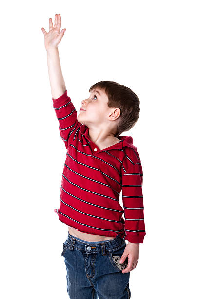 A little boy reaching arm up high against white background stock photo