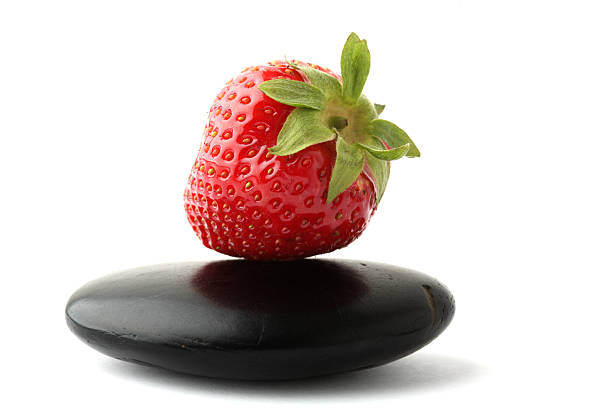 Ripe strawberry with lava stone on white background
