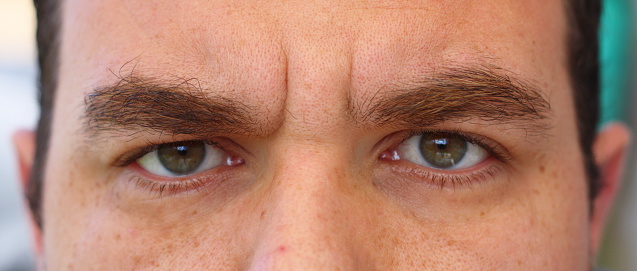 A close-up of a man showing only his eyes and his bushy eyebrows.