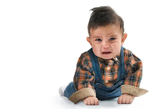 Unhappy little boy baby crawling on isolated white