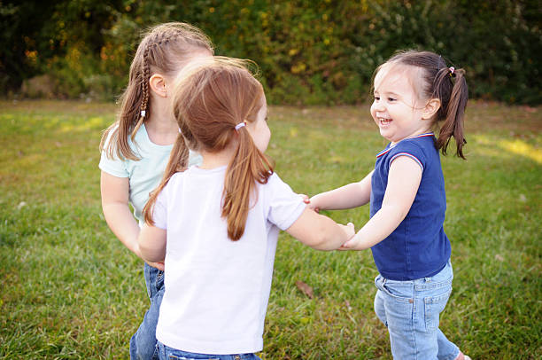 tres niñas jugando ronda infantil - child dancing preschooler outdoors fotografías e imágenes de stock