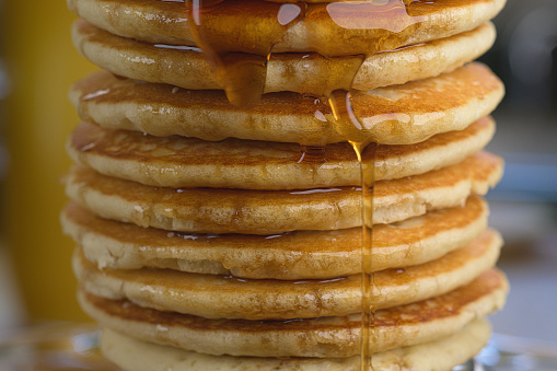 Tall stack of pancakes with rich maple syrup.