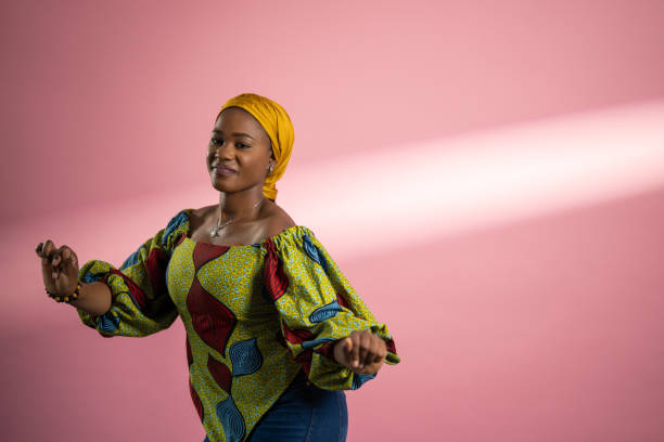 An African American Lady with a Head tie, very happy and cheerful about a successful business deal. she is wearing Ankara outfit.