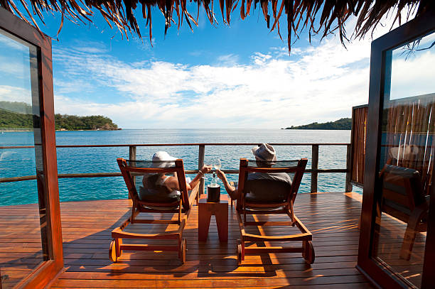 Couple relaxing in an over water bungalow Couple relaxing on sun lounges in an over water bungalow fiji stock pictures, royalty-free photos & images