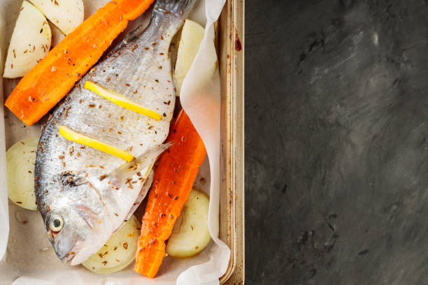 istock Fresh raw dorado fish with vegetables and lemon slices on baking sheet. Top view. Copy space 1739529772