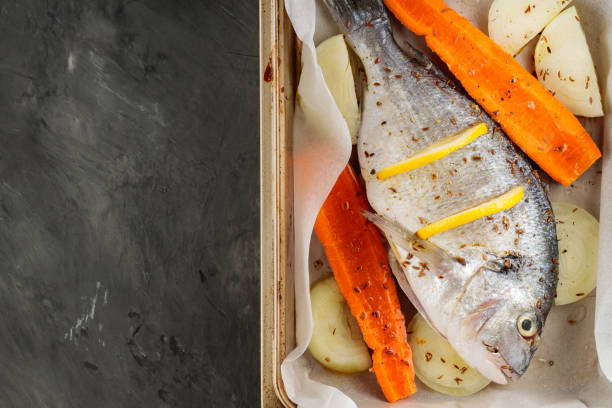 istock Fresh raw dorado fish with vegetables and lemon slices on baking sheet. Top view. Copy space 1739529795