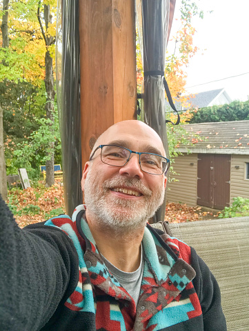 Selfie of mature man relaxing in backyard during day of autumn