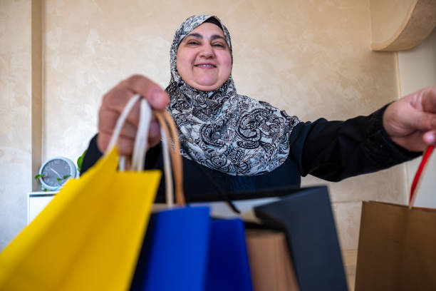 mulher árabe vestindo abaya segurando saco de compras dentro de casa na sala de estar e sorrindo - women holding shopping bag living room - fotografias e filmes do acervo