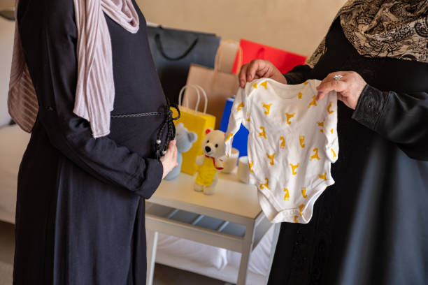 mulher árabe grávida tendo novos produtos para seu bebê presenteado por sua mãe - women holding shopping bag living room - fotografias e filmes do acervo
