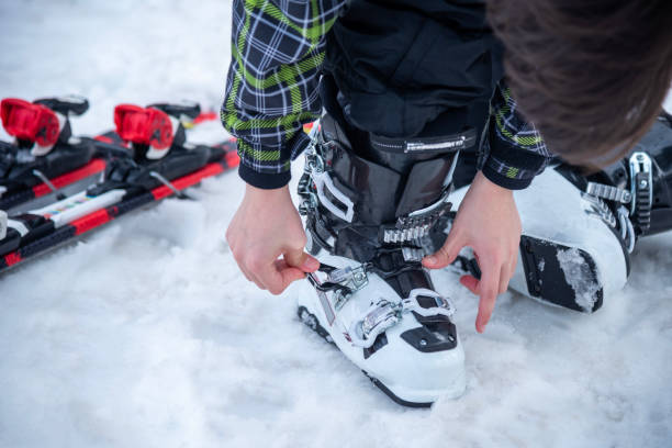 A man is wearing white ski boots in the snow