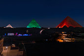 Giza pyramids illuminated with colorful lights at night.