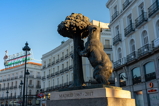 The bear and the strawberry tree in Puerta del Sol square with a poster advertising typical drinks on a building in the background. Madrid. Spain. July 29, 2023.
