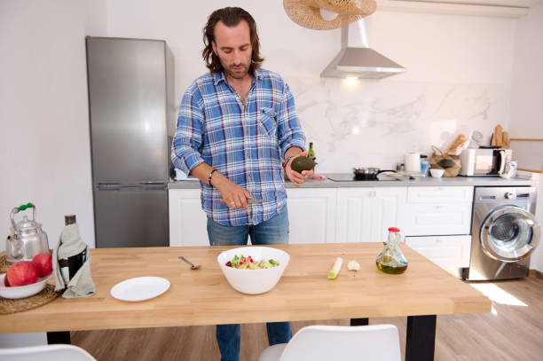 istock Handsome male chef cooking salad in the minimalist home kitchen 1739696477
