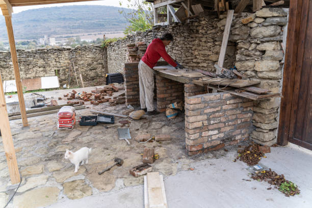 Active senior man in his backyard building his own stone barbecue.