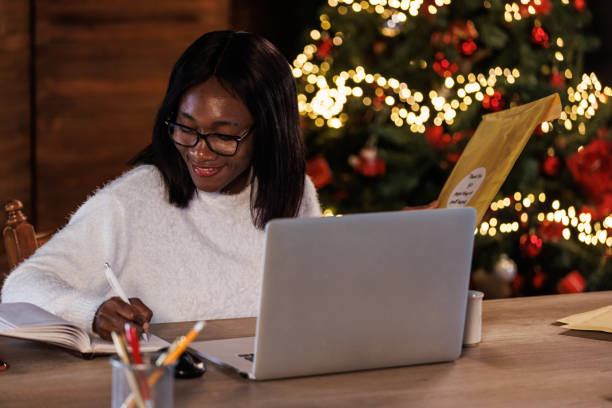 istock Young woman working for Christmas holidays at her desk, sending mail and writing notes 1739698600