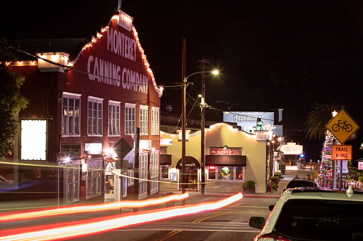 Monterey, California, USA - December 31, 2022: Night time traffic passes through the historic Cannery Row.