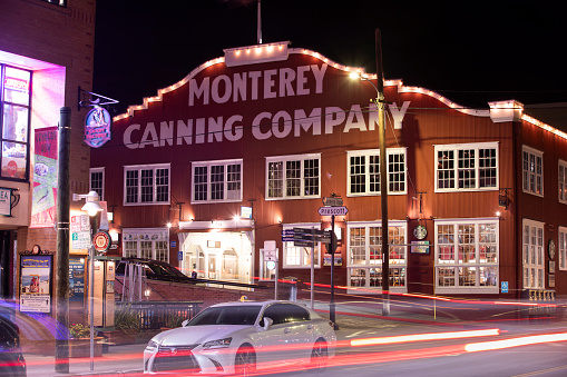 Monterey, California, USA - December 31, 2022: Night time traffic passes through the historic Cannery Row.