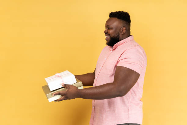 istock Man holding giving present boxes, congratulating, looking ahead with toothy smile. 1739722563