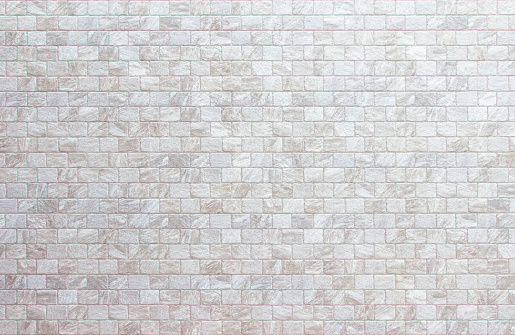 Empty background of wide cream brick wall texture. Beige old brown brick wall concrete or stone textured, wallpaper limestone abstract flooring. Grid uneven interior rock. Home decor design backdrop.