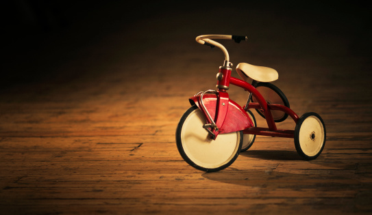 cast iron vintage tricycle  standing on a wooden floor