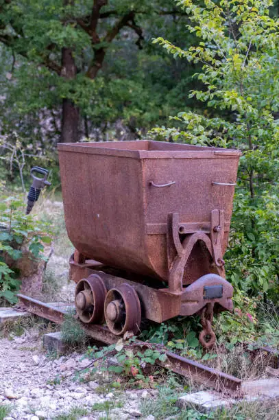 Photo of Old rusty mining cart on a rail track . Decoration in the park.