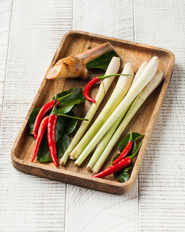 A set of lime, lemongrass and other spices for cooking Asian soups, dishes on a wooden plate on a white wooden background.