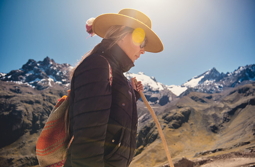 traveler hipster girl in hat with backpack exploring misty sunny rainbow mountain in Peru, South America