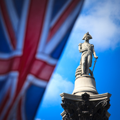 Nelson's Column in Trafalgar Square, London - with the United Kingdom flag defocussed in the foreground.