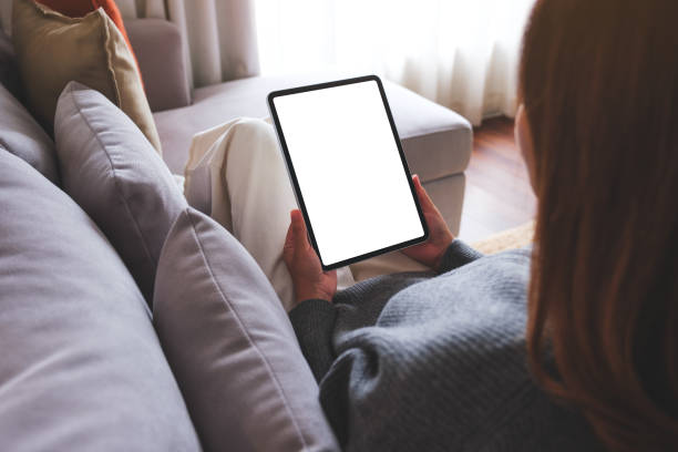 istock Mockup image of a woman holding digital tablet with blank desktop screen while lying on a sofa at home 1739955480