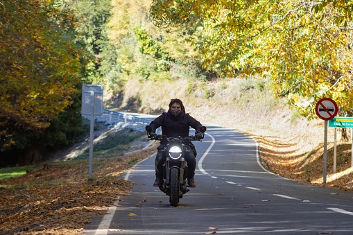 motorcyclist riding on a country road, in an autumn landscape