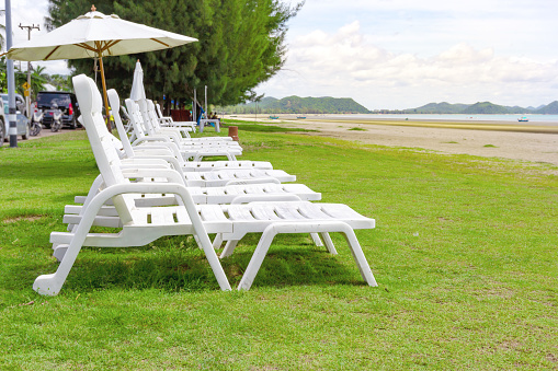 White beach chair and umbrella on tropical beach with blue sky