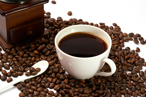 Coffee drink in a white   cup with roasted coffee beans on white background