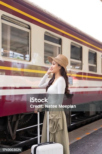 istock Asian women waiting for train station and carrying a suitcase planning happy holiday vacation 1740003024