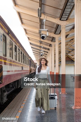 istock Asian women waiting for train station and carrying a suitcase planning happy holiday vacation 1740003551