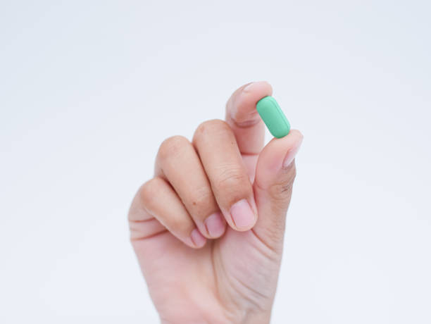 istock Hand holding green medical pills on white background 1740004653