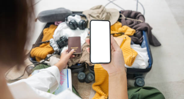 istock Woman prepare travel clothes using telephone screen blank mockup 1740005214