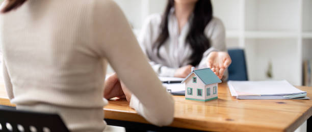 istock Real estate agent and client explain mortgage loan contract. Make a contract for hire purchase and sale of a house. home mortgage loan insurance concept. 1740059847